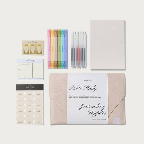 A Bible Study journaling supplies kit by Alastair, arranged neatly on a light beige background. The kit includes a beige envelope, a white paper band with 'Bible Study Journaling Supplies' written on it, a stack of cream-colored sticky notes, a sheet of gold foil tabs, a pastel highlighter pen set, a set of clear pens with colored ink, and a blank embossed journal page.