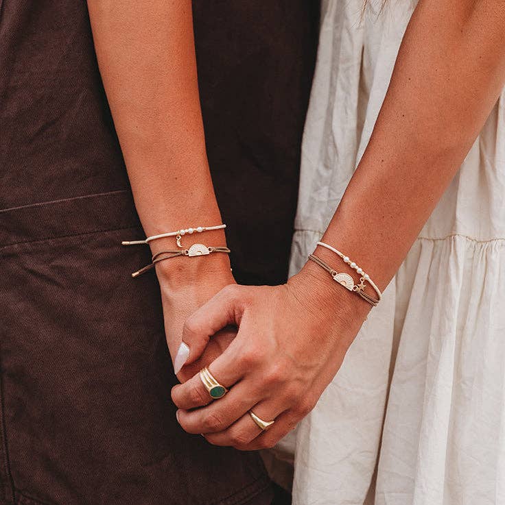 Close-up of two people holding hands with visible jewelry.
