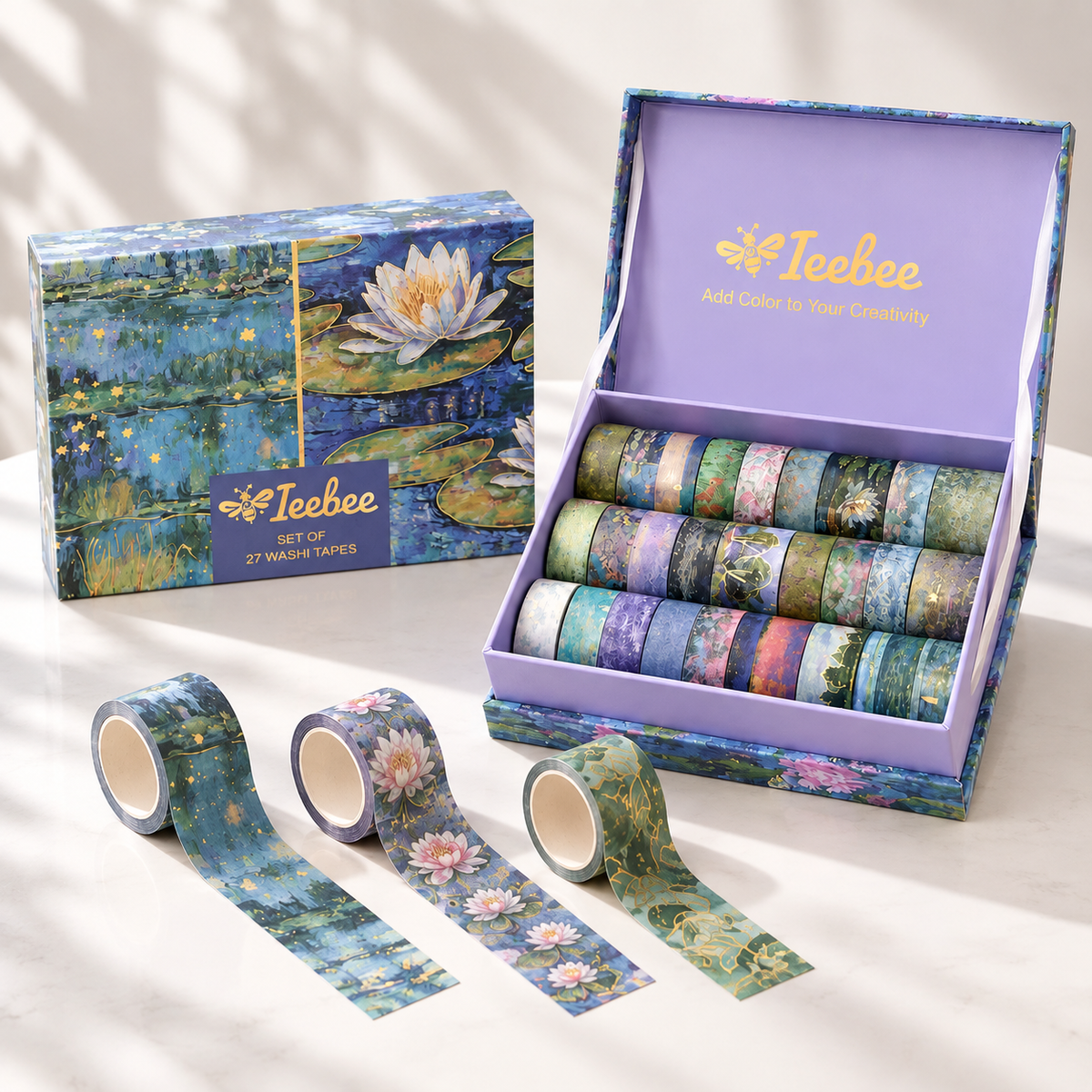 A boxed set of washi tapes by Ieebee with a water lily painting design, shown open with multiple rolls inside and three loose rolls in front on a light surface.