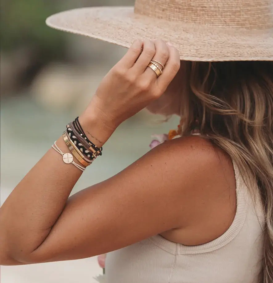Person wearing a straw hat and multiple bracelets with a blurred natural background
