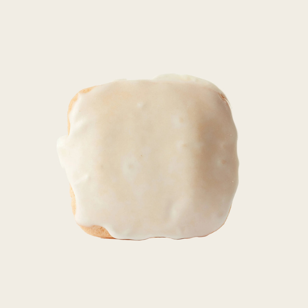 Square piece of bread with white frosting on a white background