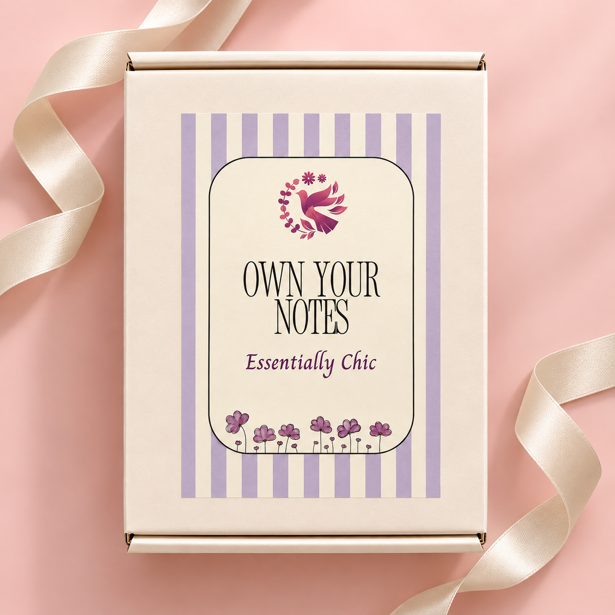 A cream-colored product box with lavender purple stripes and a central label that reads 'OWN YOUR NOTES' and 'Essentially Chic,' tied with a cream satin ribbon on a soft pink background. Curated by Amazing Robin Gifts.