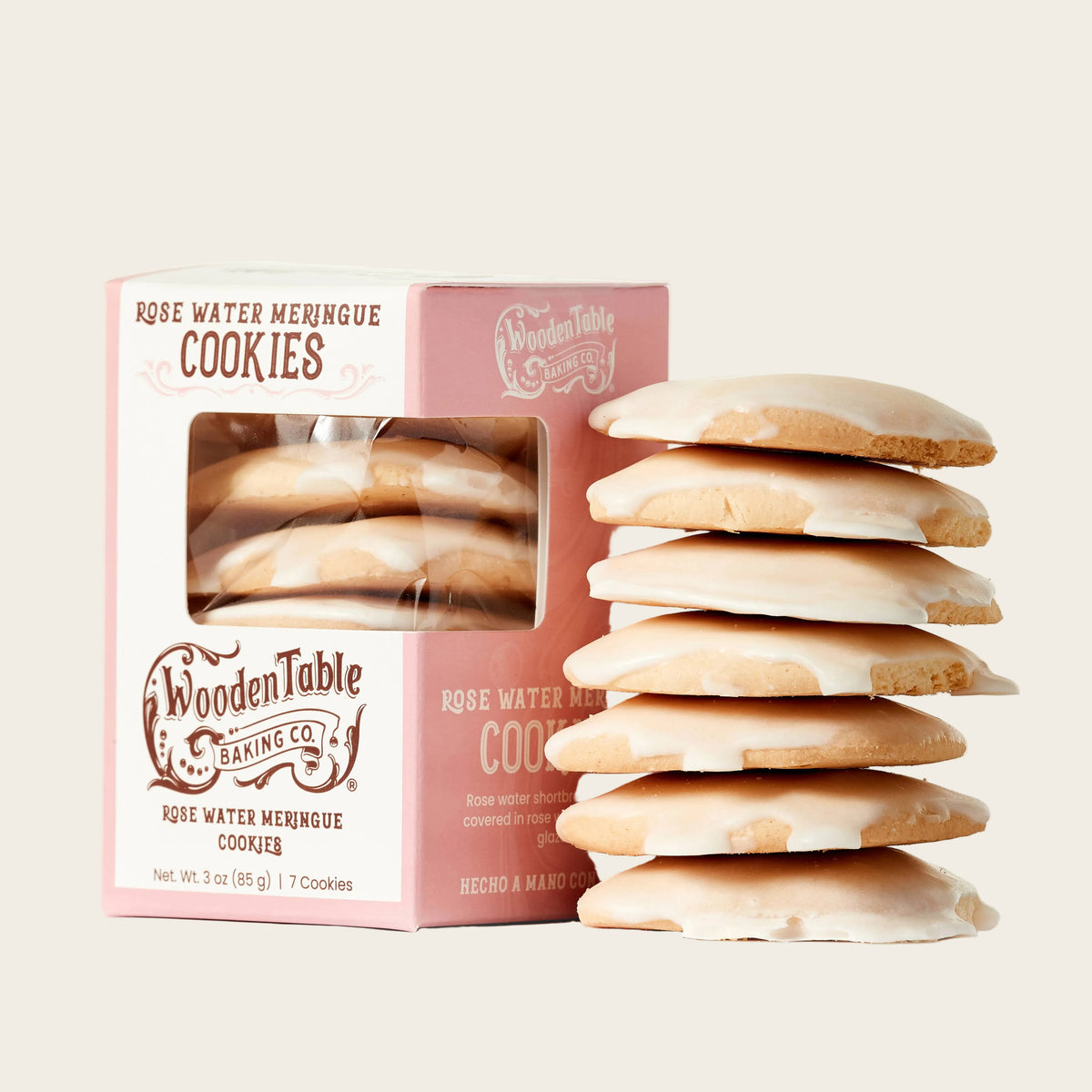 A box of Wooden Table Baking Co. Rose Water Meringue Cookies with a tall stack of the cookies displayed in front on a clean white background.
