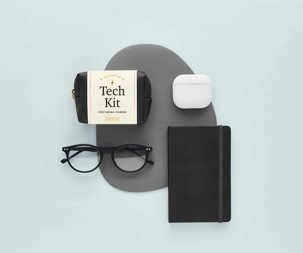 Tech Kit with a pair of eyeglasses, black journal and air pods.