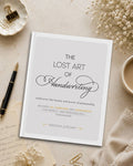 A book titled 'The Lost Art of Handwriting' by Brenna Jordan is displayed in a styled flat-lay arrangement on a beige surface with a black pen, paper clips, dried flowers, and a cup of coffee.